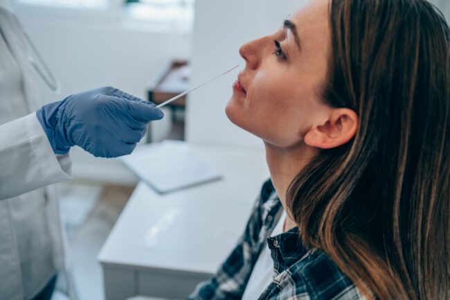 Young woman getting tested for coronavirus/Covid-19 at medical clinic.