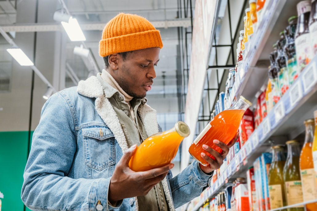 Man choosing between organic and processed juices.