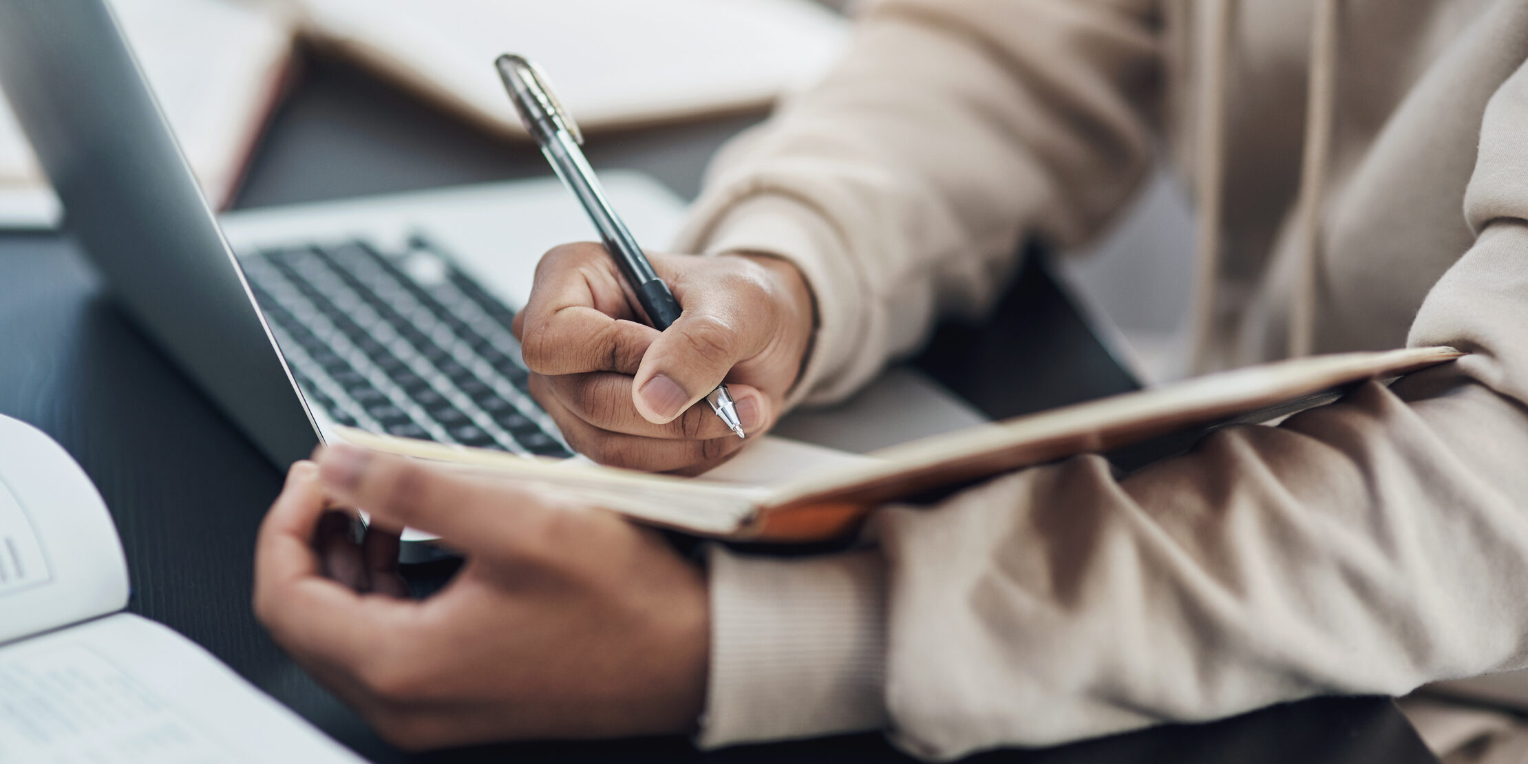 Shot of an unrecognisable man writing in a notebook while working from home