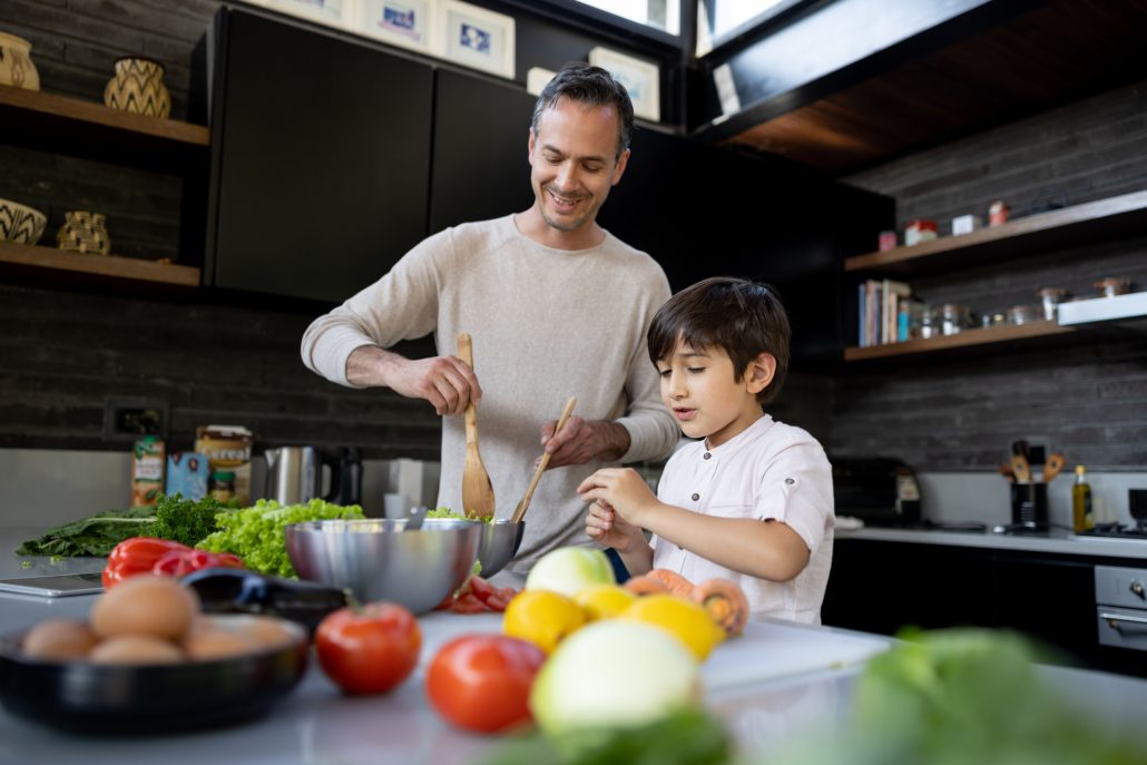 Happy Latin American father and soon cooking together in the kitchen at home