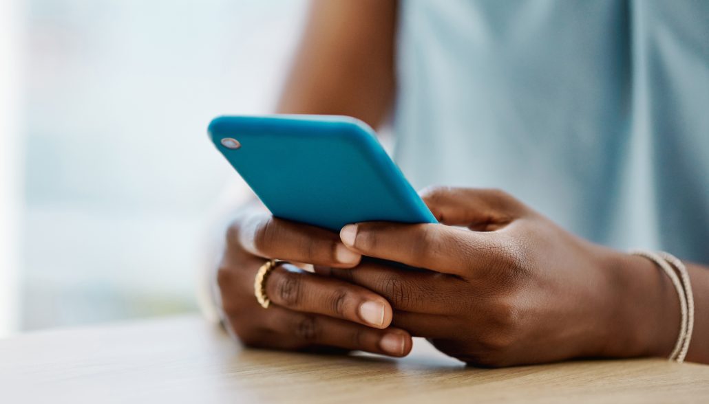 African woman using a blue cellphone in an office alone