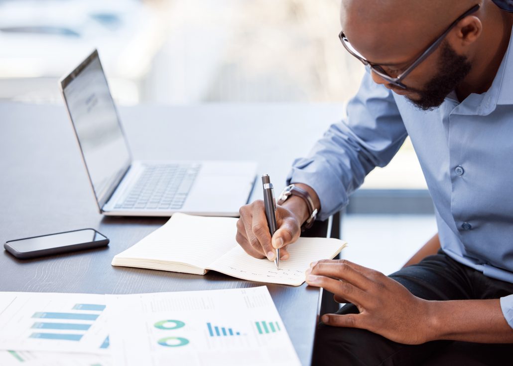 Shot of a businessman making notes while sitting at his desk