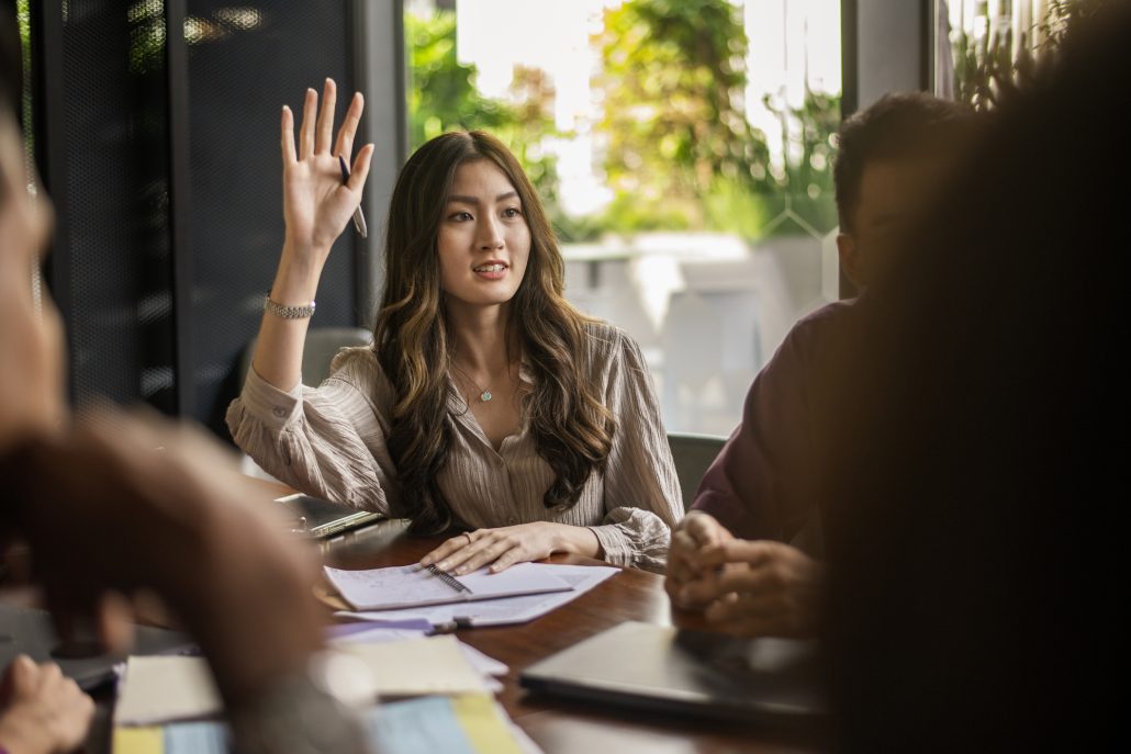 Business lady raising hand and asking a question during a discussion