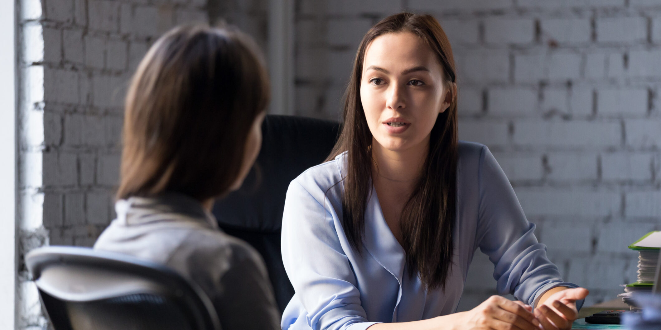 Serious professional female advisor consulting client at meeting talking having business conversation or making offer, insurer giving advice, mentor teaching intern, hr speaking at job interview
