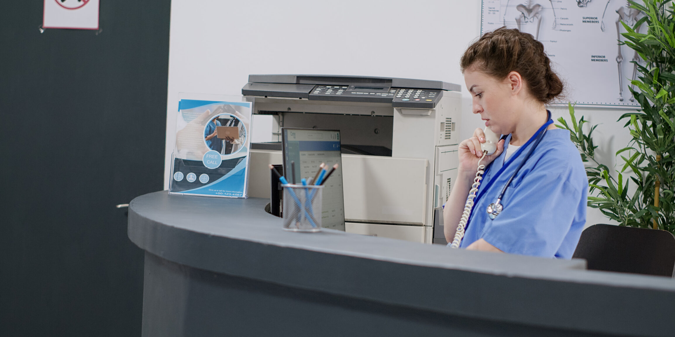 Woman nurse answering landline phone call at reception counter